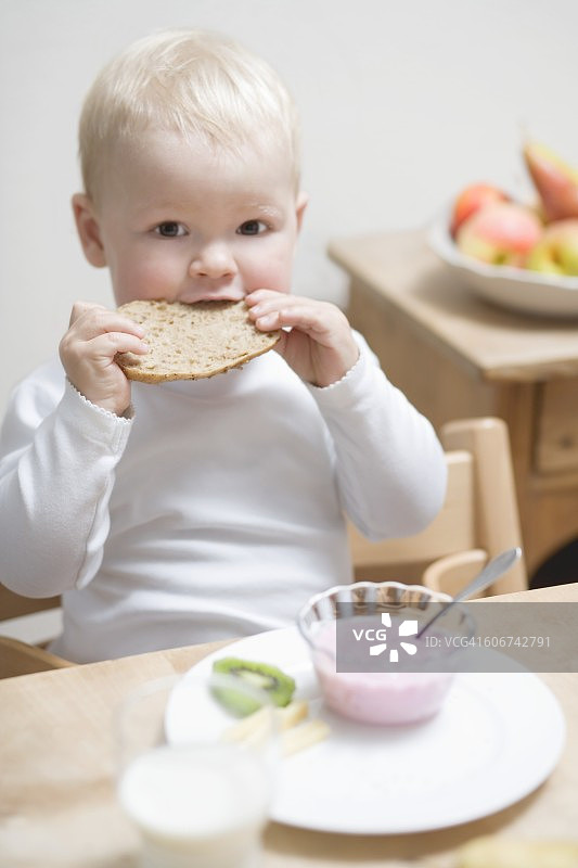 小男孩早餐吃半个面包卷图片素材