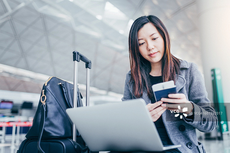 在机场拿着护照使用笔记本电脑的女人图片素材