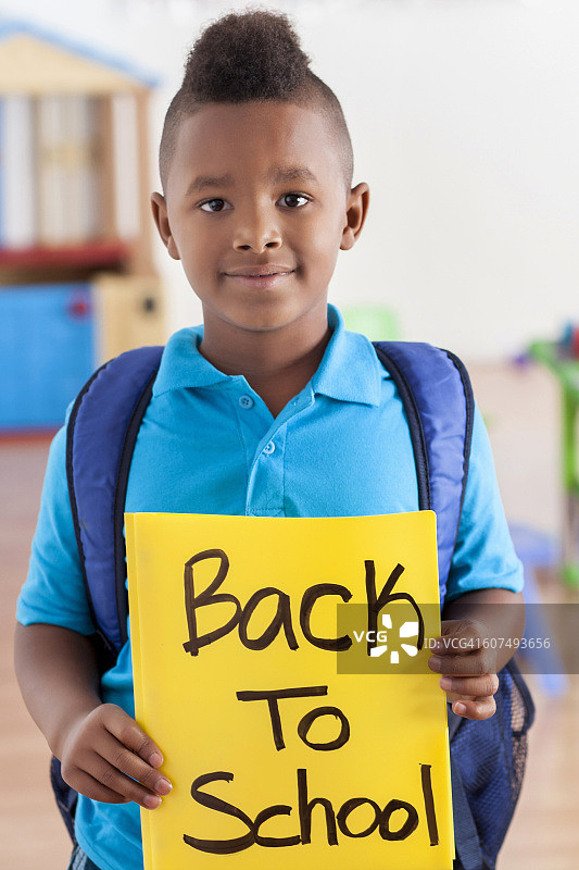 男孩在学校手持“返校”标牌图片素材
