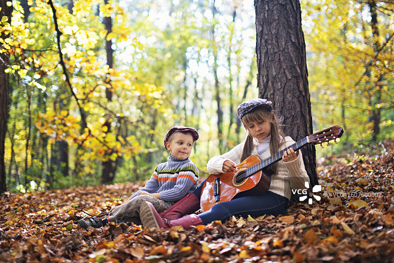 兄妹在秋日森林里一起弹吉他图片素材