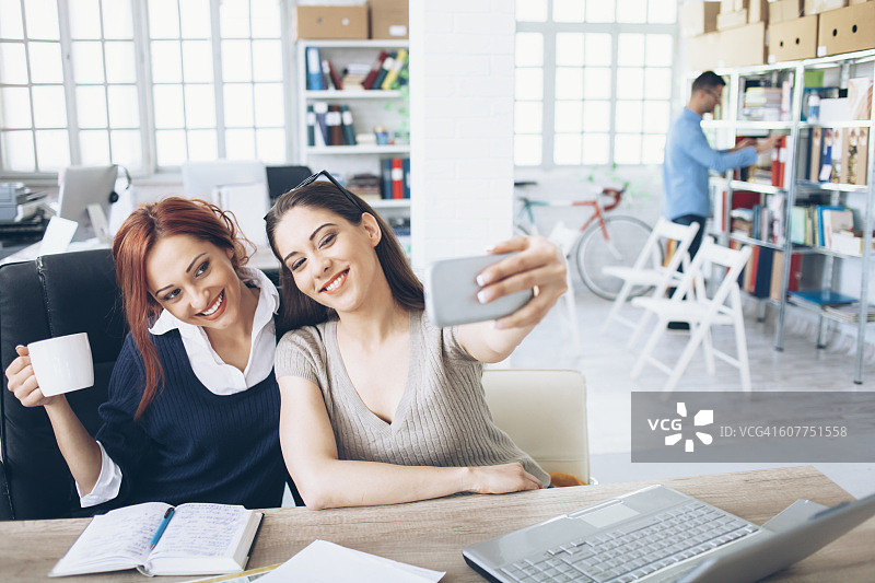 两位微笑的女同事在办公室自拍图片素材