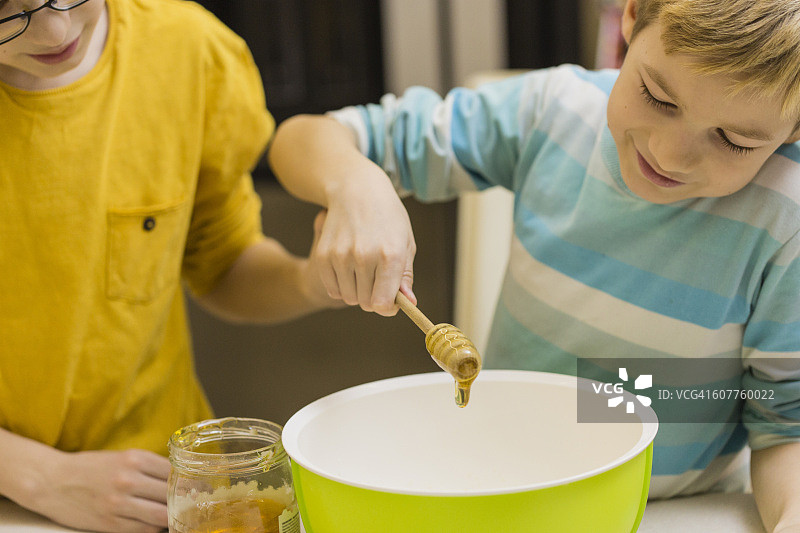孩子们倒蜂蜜到碗里，烘烤饼干图片素材
