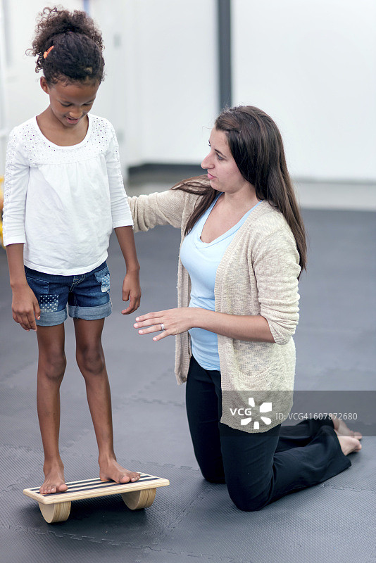 成年女治疗师帮助非裔美国女孩保持平衡图片素材