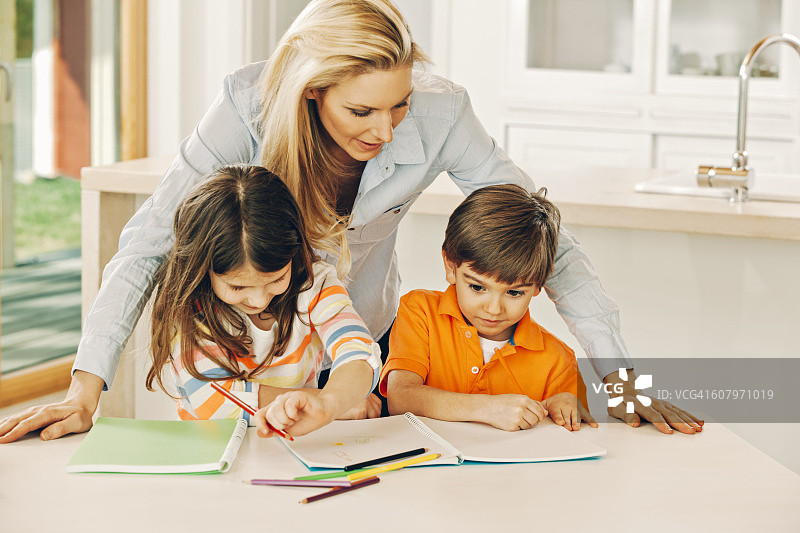 母亲看着正在涂色的孩子们图片素材