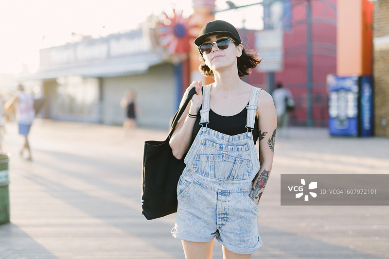 美国纽约州科尼岛，日落时分在木板路上的年轻女人图片素材