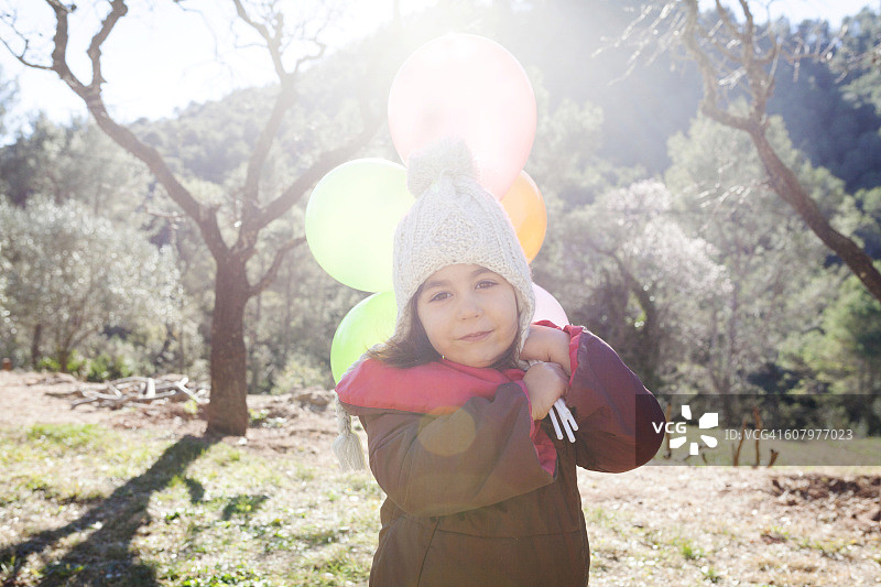 西班牙加利法：戴着绒球帽的小女孩肖像，手拿气球图片素材