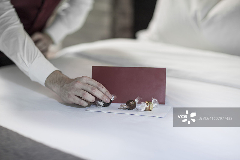 管家在酒店床上放巧克力图片素材