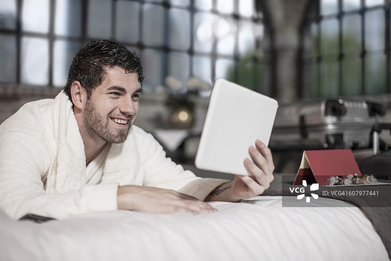 在酒店床上使用平板电脑的男人图片素材