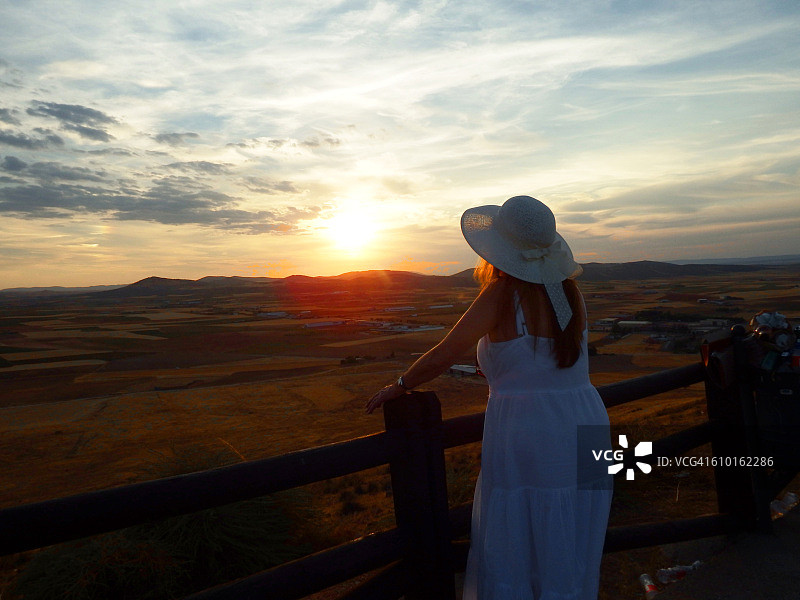 戴着帽子看日落的漂亮女人图片素材