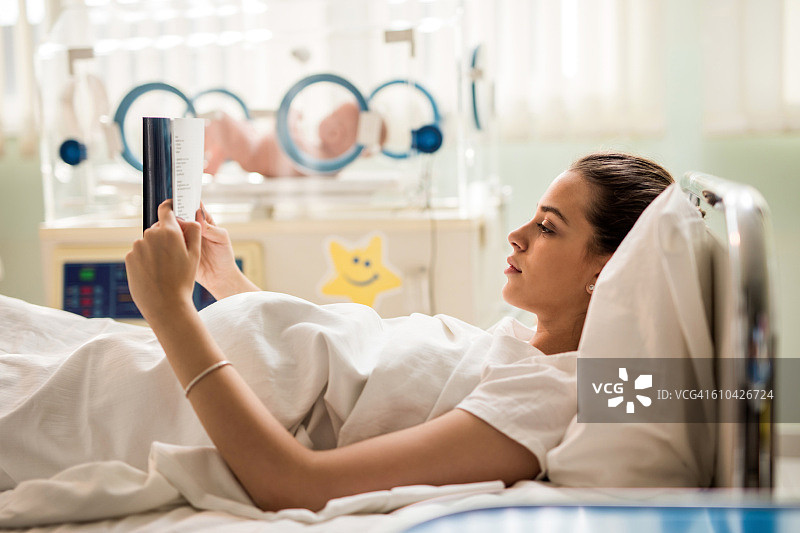 年轻母亲在卧室里读书图片素材