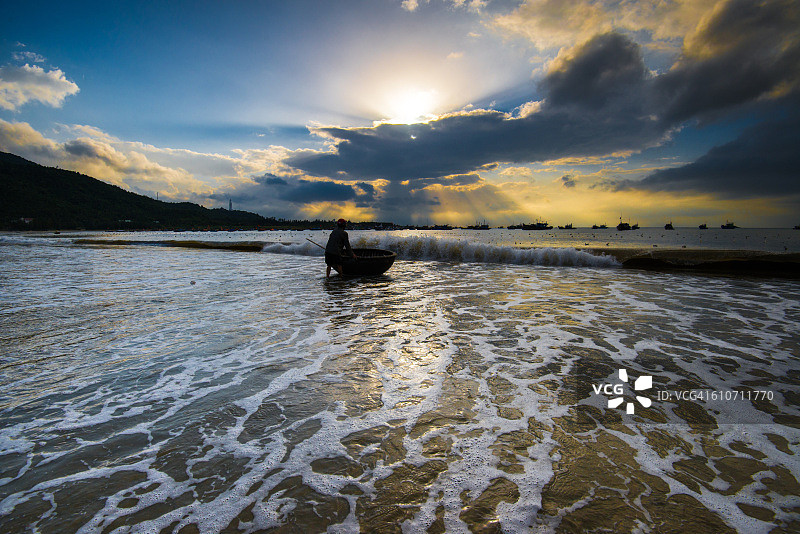 渔民在越南岘港美溪海滩的日出中劳作图片素材