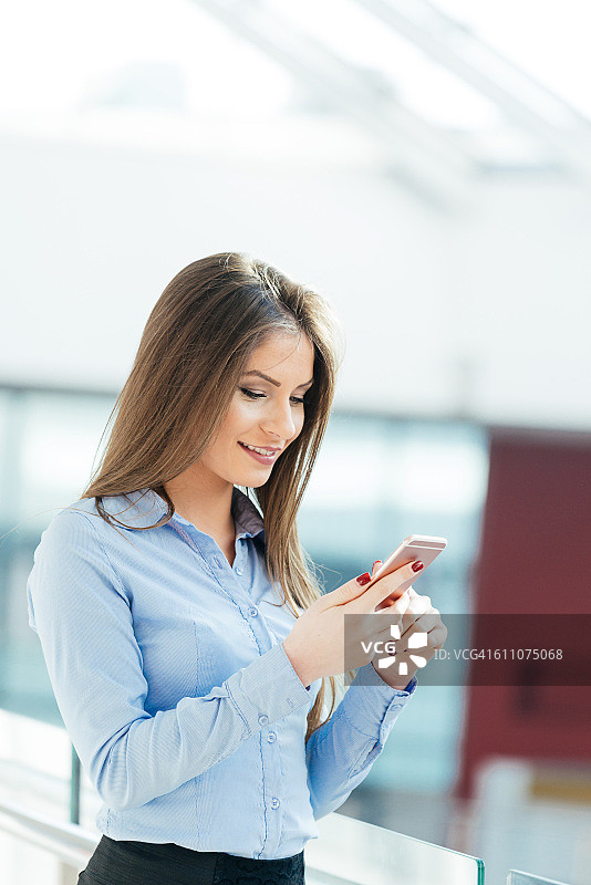 穿着正式的女人在智能手机上输入在线消息图片素材