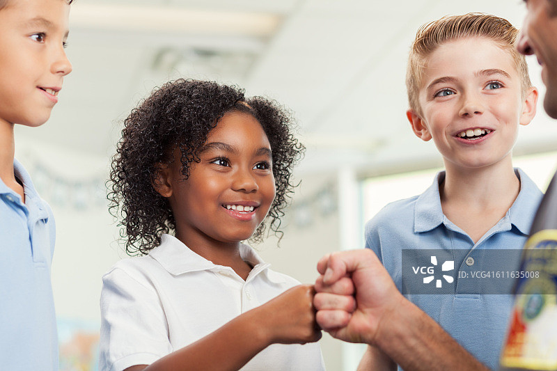 可爱的小学生与学校保安碰拳图片素材