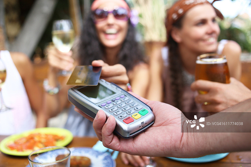 在酒吧使用信用卡进行非接触式支付的快乐女性图片素材