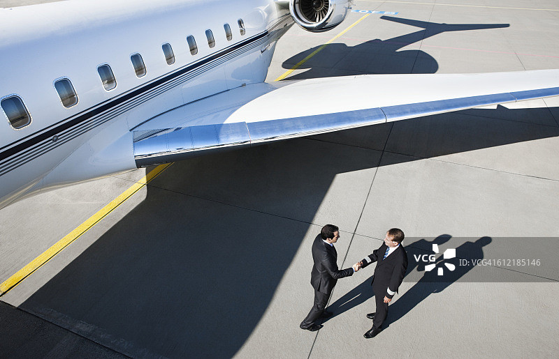商人和飞行员在飞机旁握手图片素材