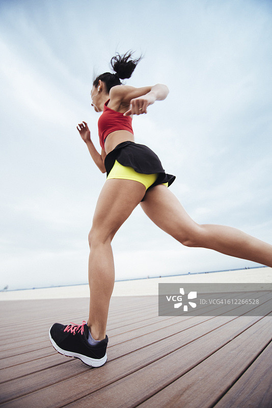 在海滩跑步的年轻健身女性图片素材