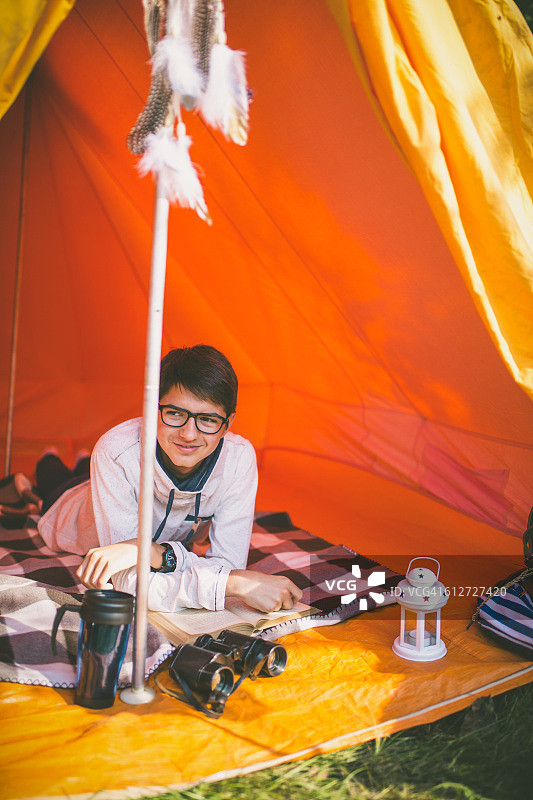 在露营帐篷里阅读旅行指南的露营男人图片素材