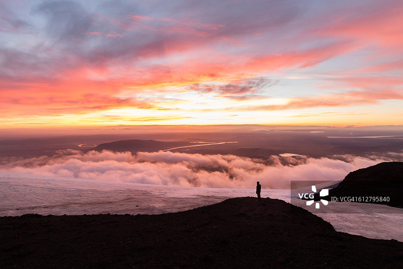 男人站在冰岛火山日落的山顶云端之上图片素材