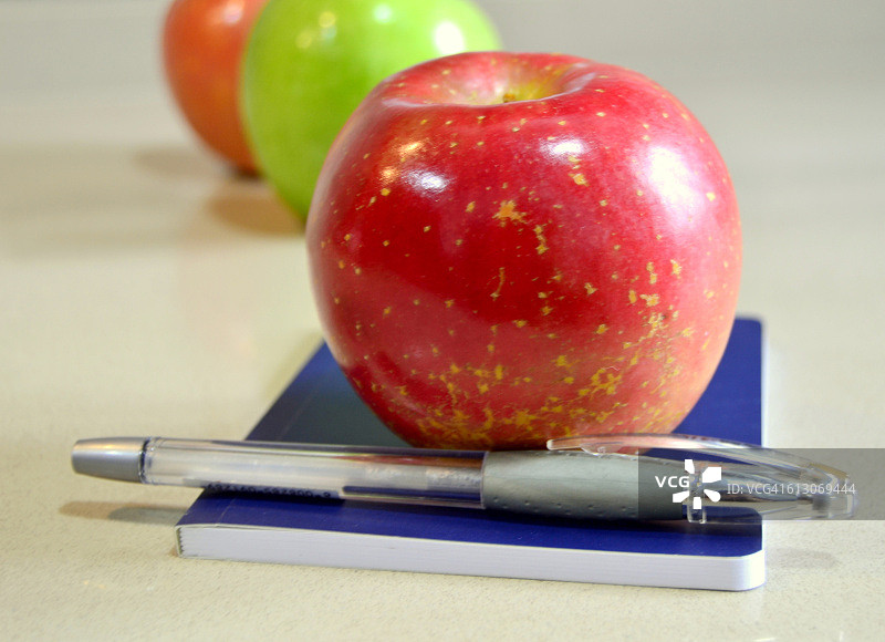 笔记本和钢笔上的红色苹果特写图片素材