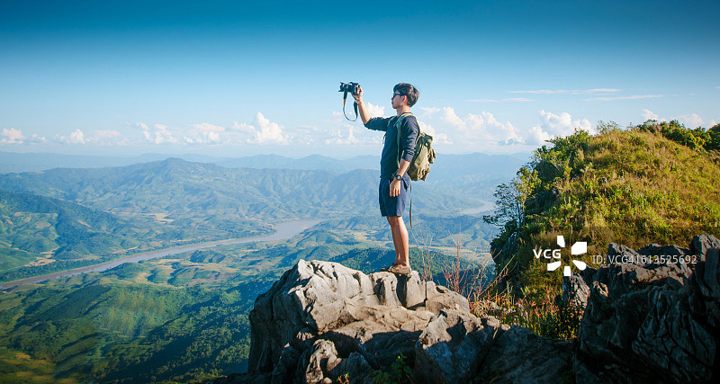年轻旅行者站在山上欣赏日落图片素材