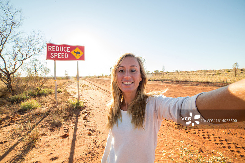 站在骆驼警告标志旁的年轻女人的自拍图片素材