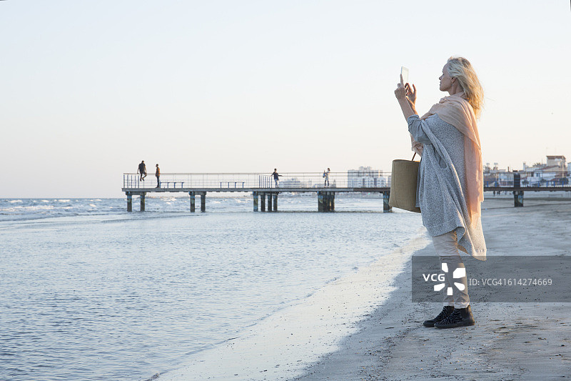 女人在海边用平板电脑拍照图片素材