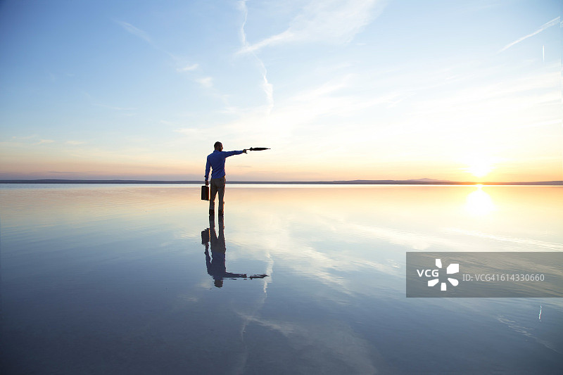 在盐湖上撑着黑色雨伞的商人图片素材