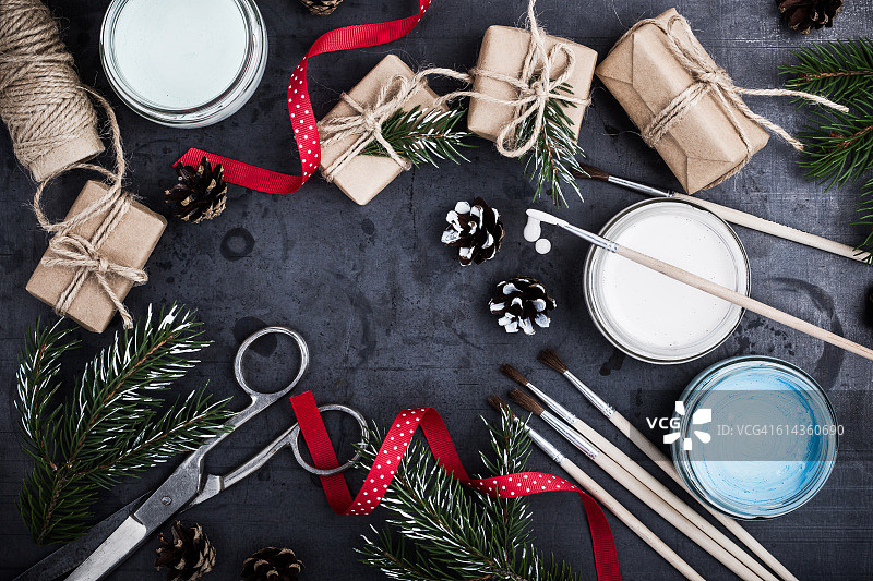 准备圣诞节，用天然礼物装饰，留有文案空间。用于绘画的画笔、丝带、剪刀、颜料、牛皮纸包装的礼品盒、小树枝的顶视图图片素材