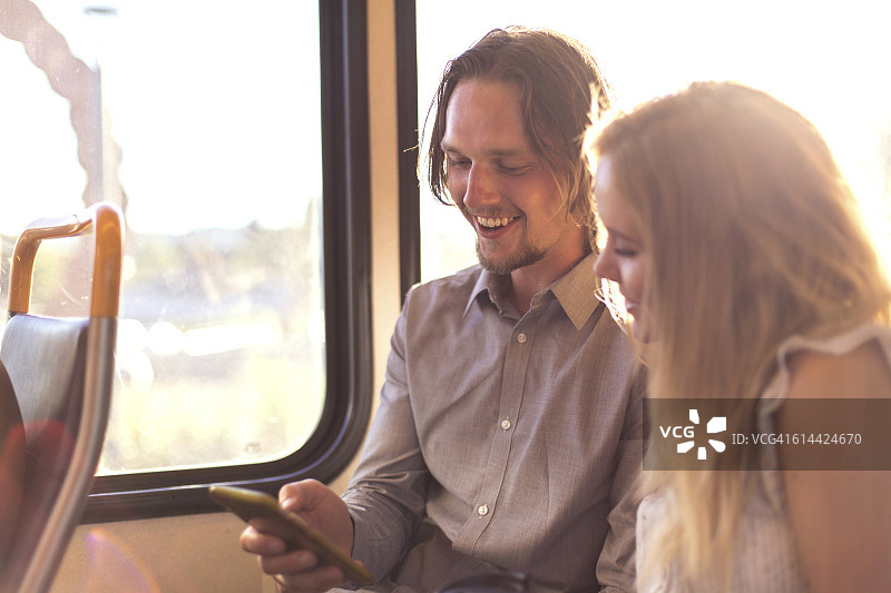 异性情侣在公共交通工具上使用智能手机图片素材