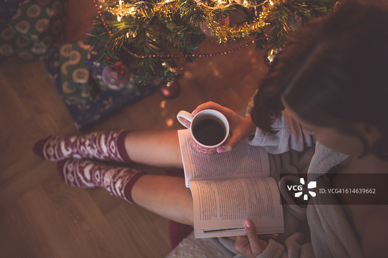 在圣诞树旁看书喝咖啡的女孩图片素材
