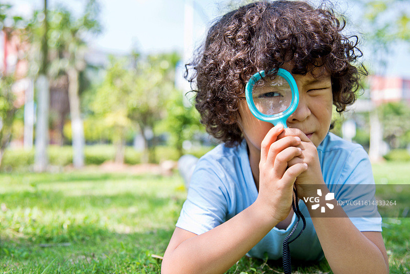 在公园里拿着放大镜的小男孩图片素材