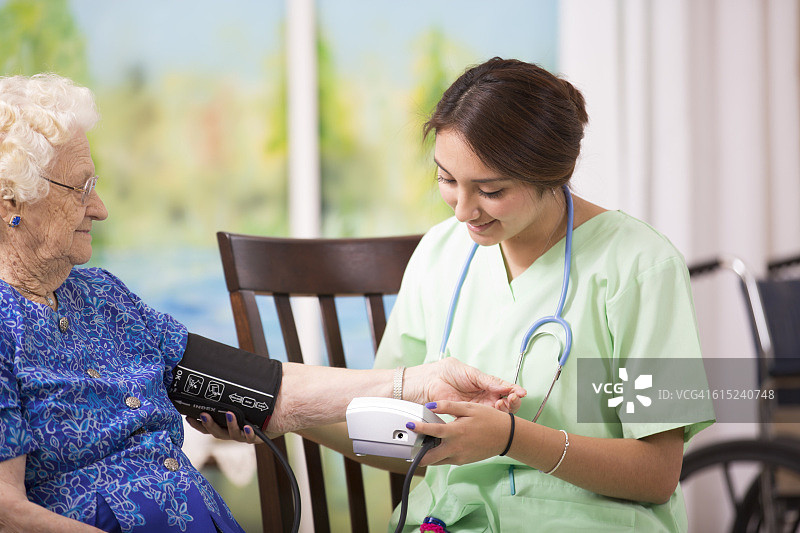 家庭护士检查老年妇女的血压图片素材