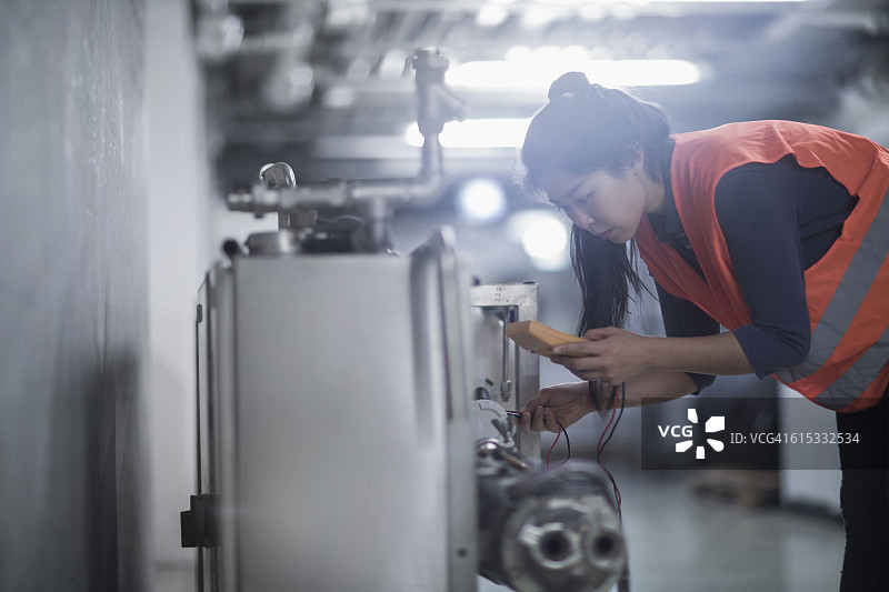 在工业工厂用万用表检查机器的年轻女工程师，德国弗莱堡图片素材