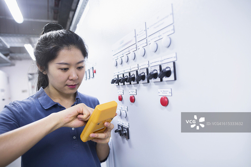 弗莱堡工业工厂：年轻女工程师用万用表检查控制面板图片素材