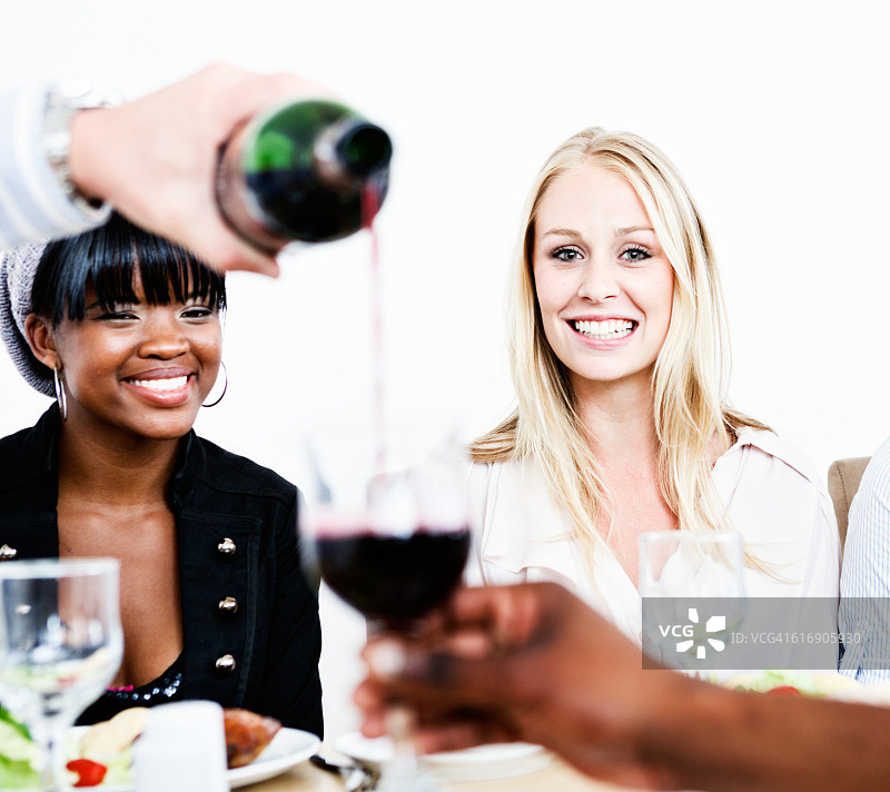 为微笑的年轻客人倒红酒图片素材