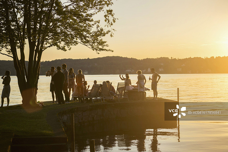 在德国巴伐利亚，一群年轻的朋友在日落时于湖边聚会图片素材