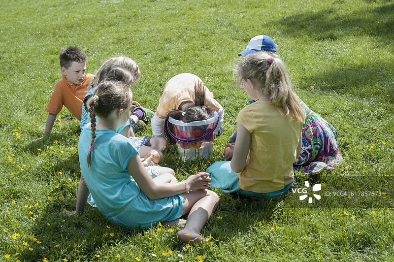 德国巴伐利亚慕尼黑：女孩试图用嘴从水桶里拿出苹果图片素材
