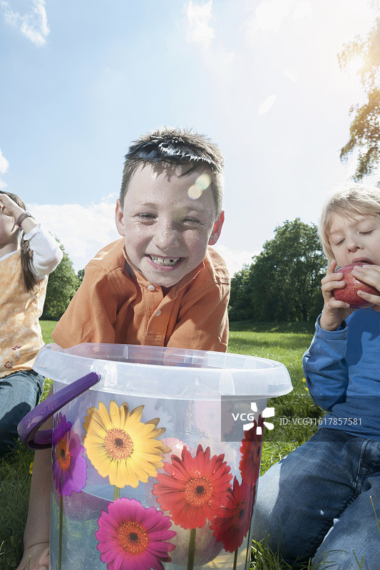 男孩试图用嘴从桶里拿出苹果，德国巴伐利亚慕尼黑图片素材