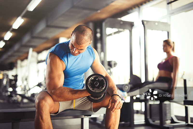 健壮的年轻男人在健身房举哑铃图片素材