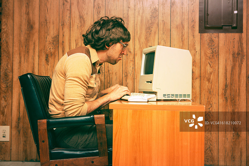 有趣的呆子男人正专注地看着老式电脑图片素材
