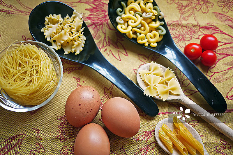 不同形状的意大利生面食、生鸡蛋和樱桃番茄图片素材