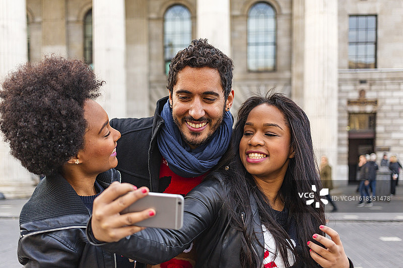 朋友们穿着节日毛衣在圣诞购物时自拍图片素材