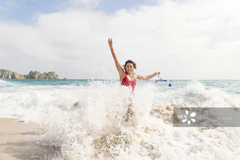 年轻女人在康沃尔波斯科诺海滩被海浪拍打图片素材