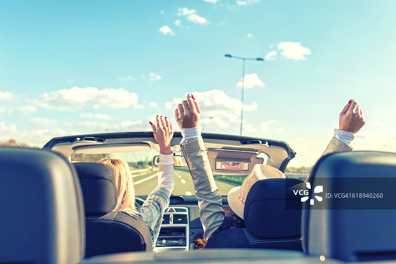 女性朋友在敞篷车里举起双手图片素材