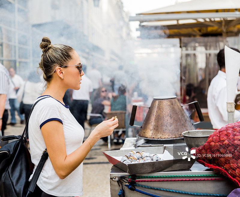 年轻女人在里斯本街头购买栗子图片素材