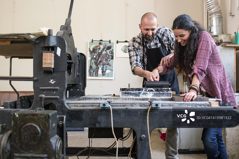 情侣石印工人使用印刷机在车间工作图片素材