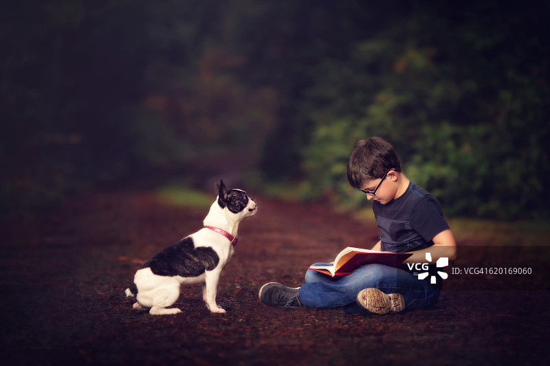 男孩和他的狗在户外读书图片素材