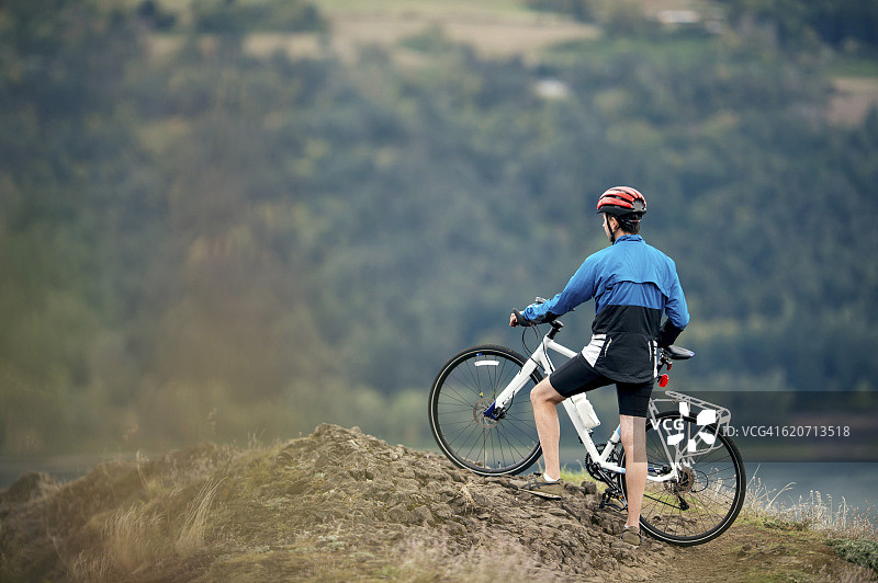 骑山地自行车的成年男子眺望山谷图片素材