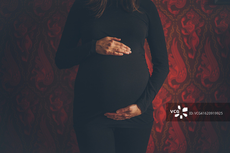红色壁纸背景下的中年孕妇肖像图片素材
