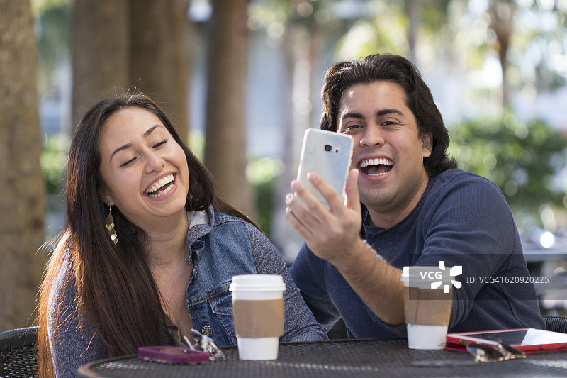 两名年轻人在户外咖啡馆喝热饮图片素材